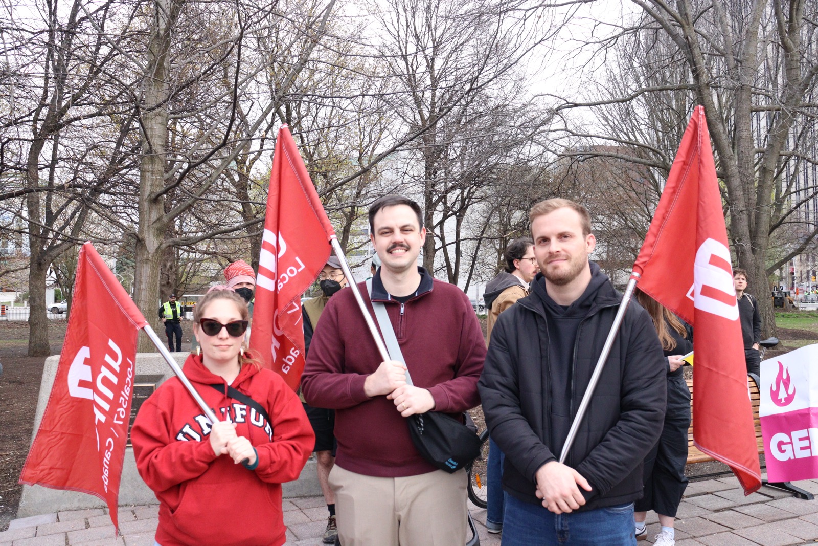 A picture of three Unifor 567 Board Members including the President, Vice President, and Chief Steward holding Unifor 567 Flags