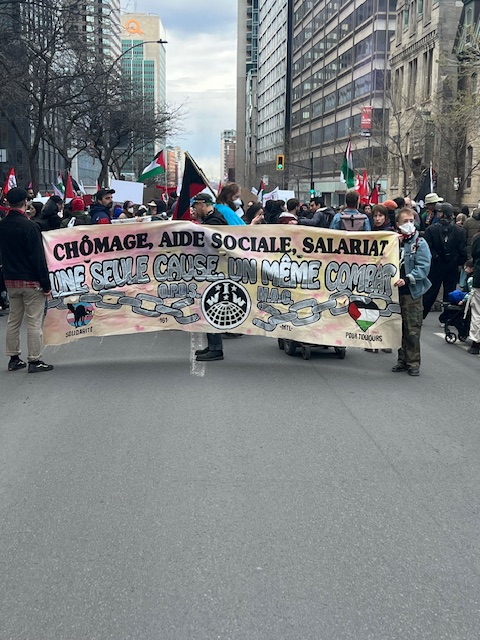 A group of people holding a banner that reads "Chômage, Aide Social, Salariat. Une Suele Cause, Un Même Combat" with the image of a broken chain underneath.